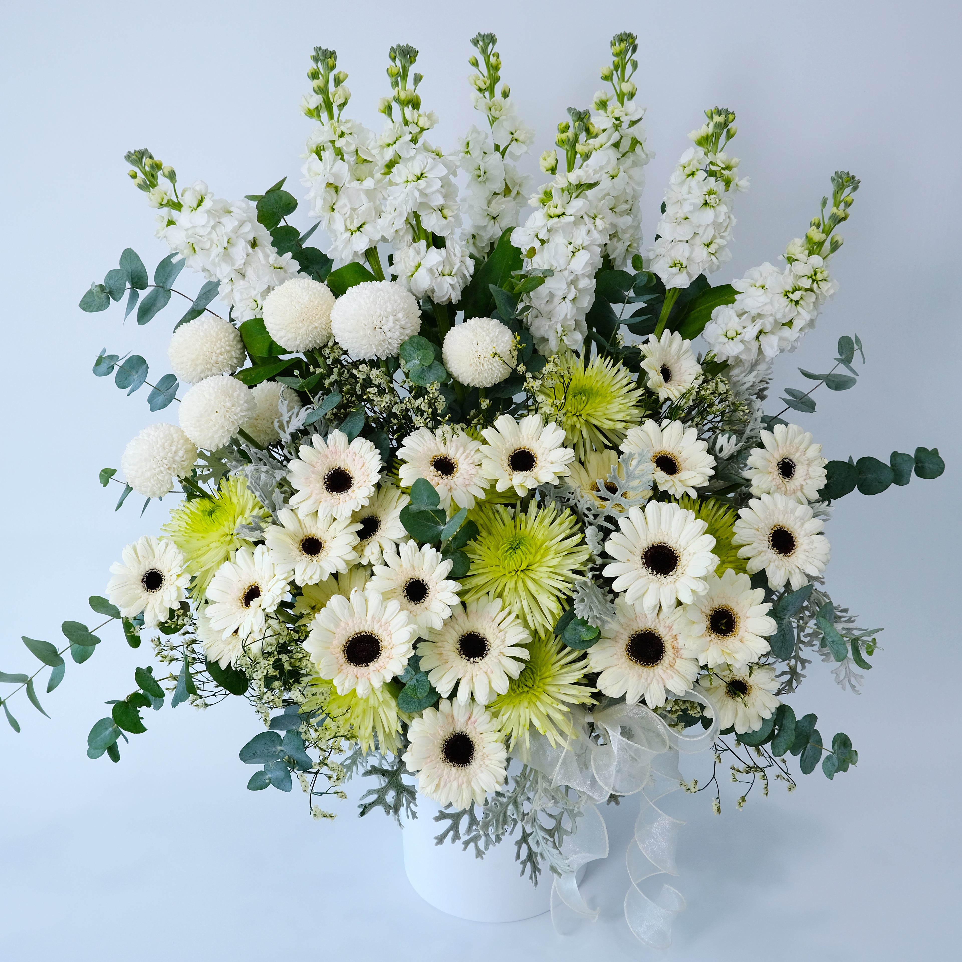 Bouquet of white, green, and yellow flowers on a light blue background