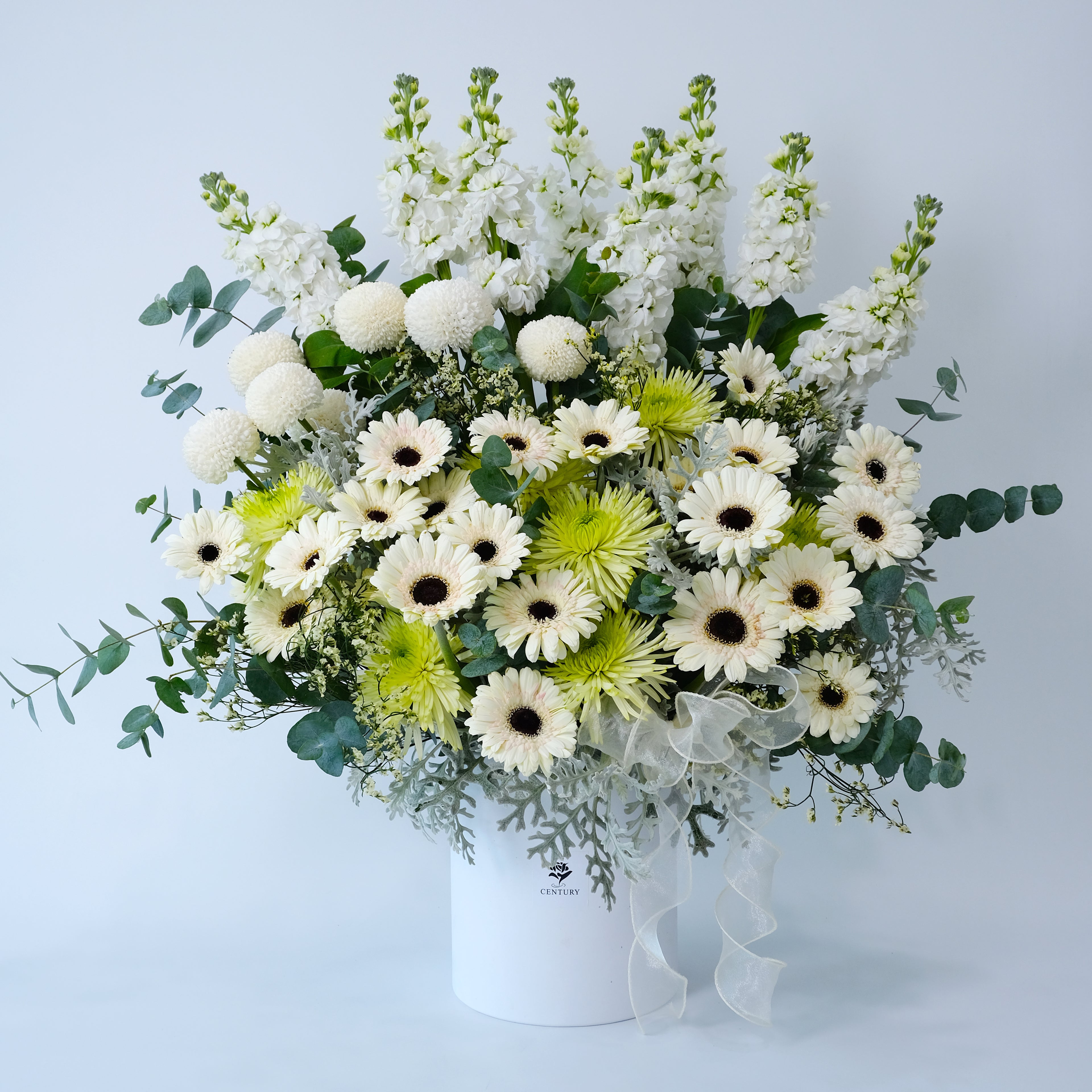 Bouquet of white, green, and yellow flowers in a white container on a light blue background