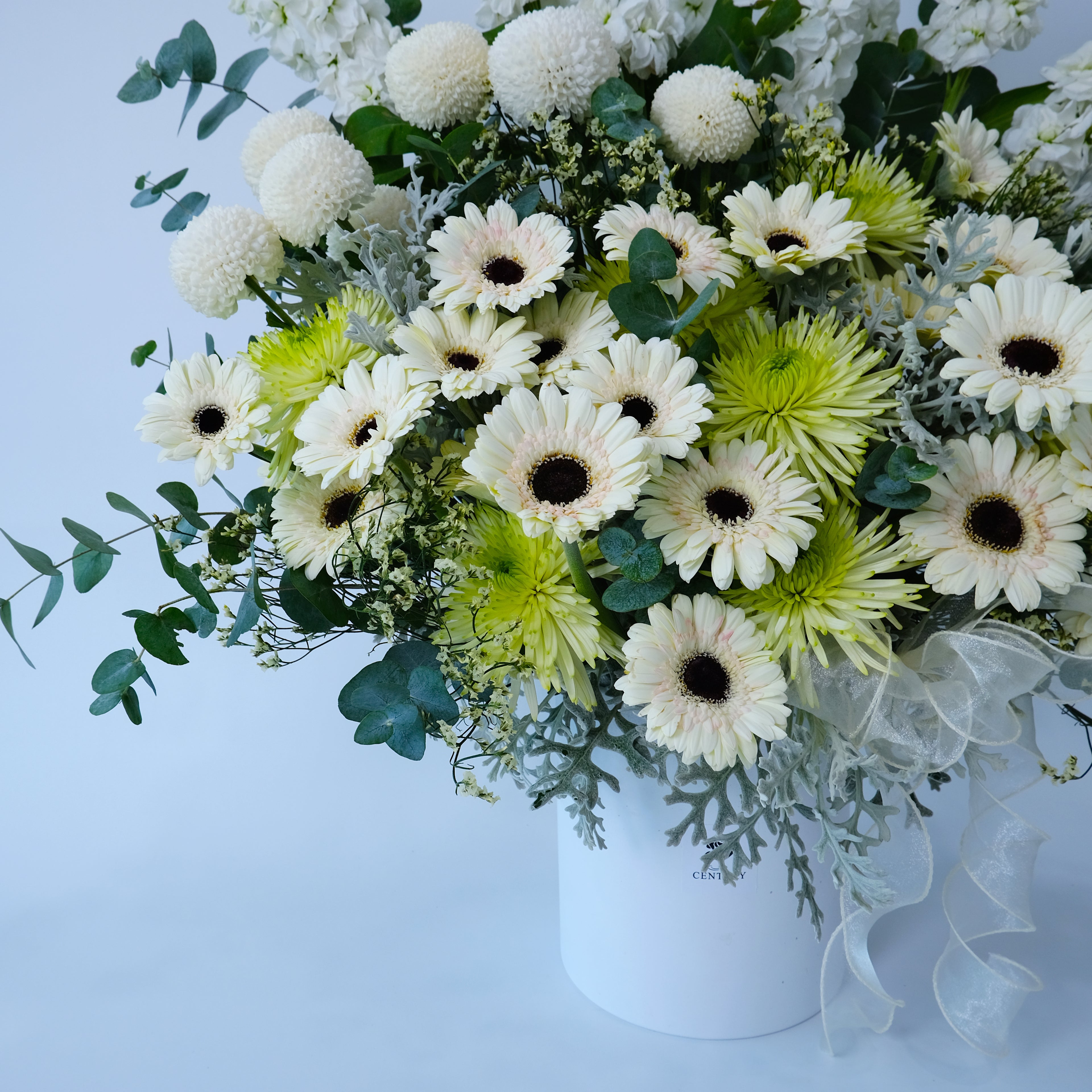 Bouquet of white and green flowers in a white vase on a light blue background