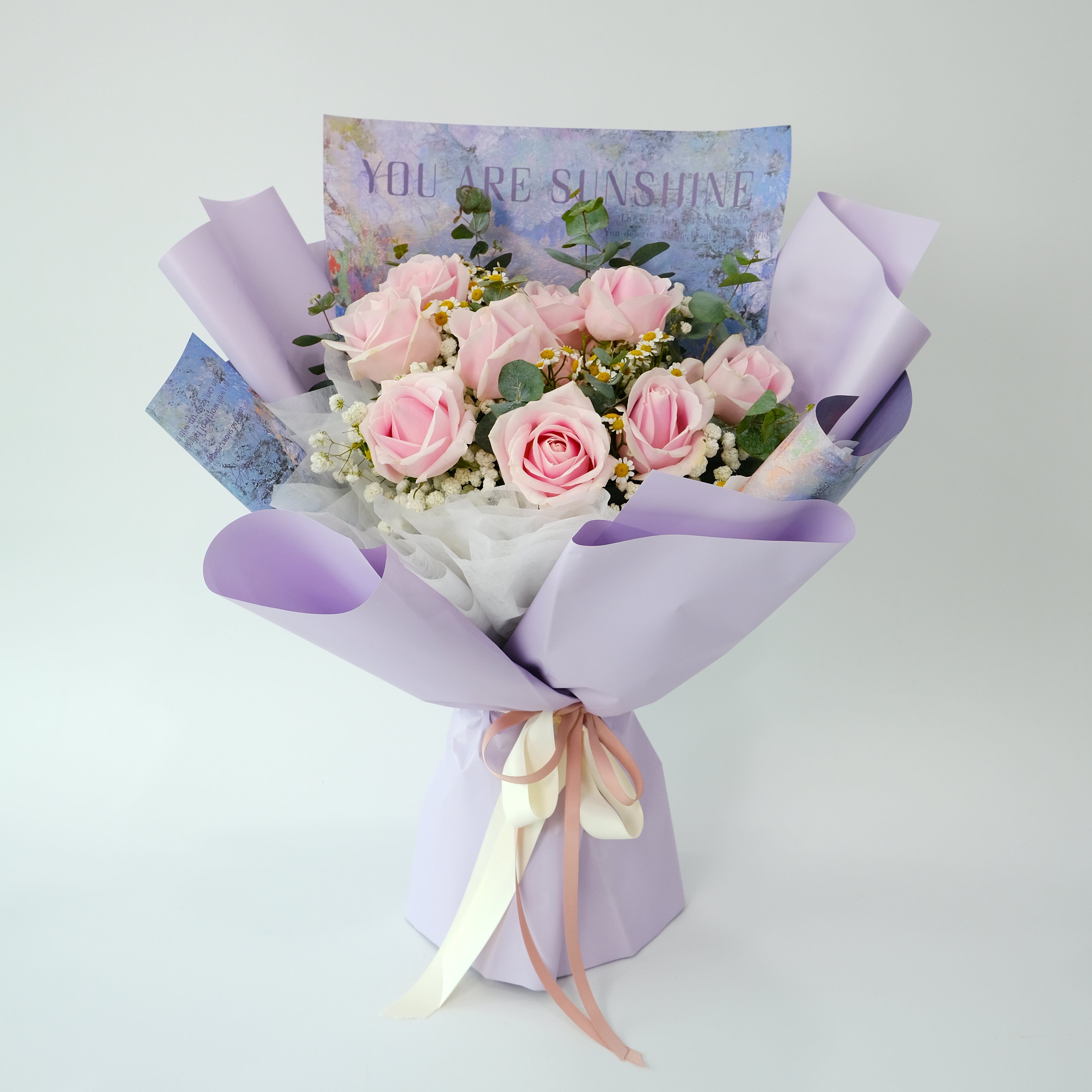 Bouquet of pink roses with a card on a light gray background
