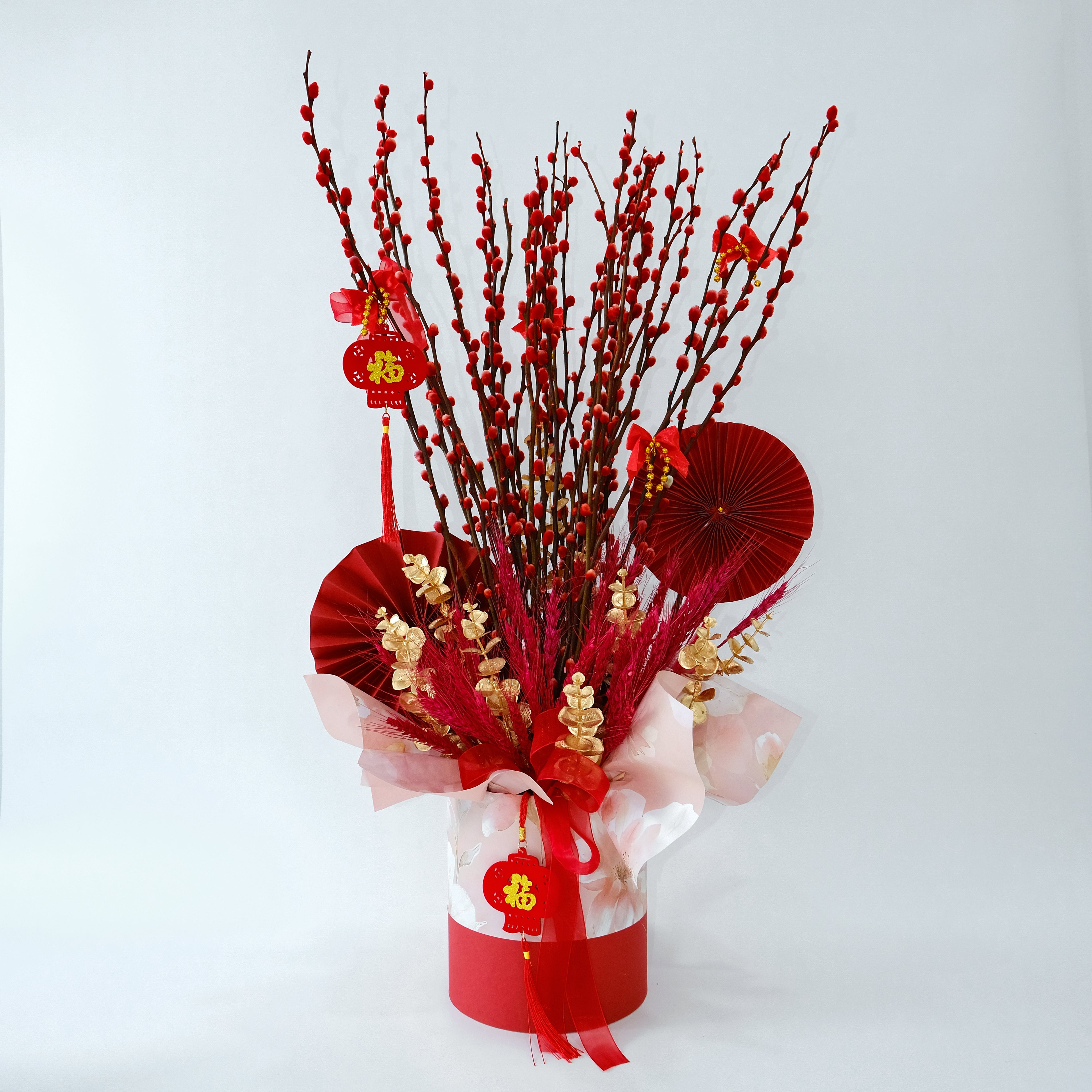 Decorative arrangement with red branches, red paper fans, and red ribbons on a white background