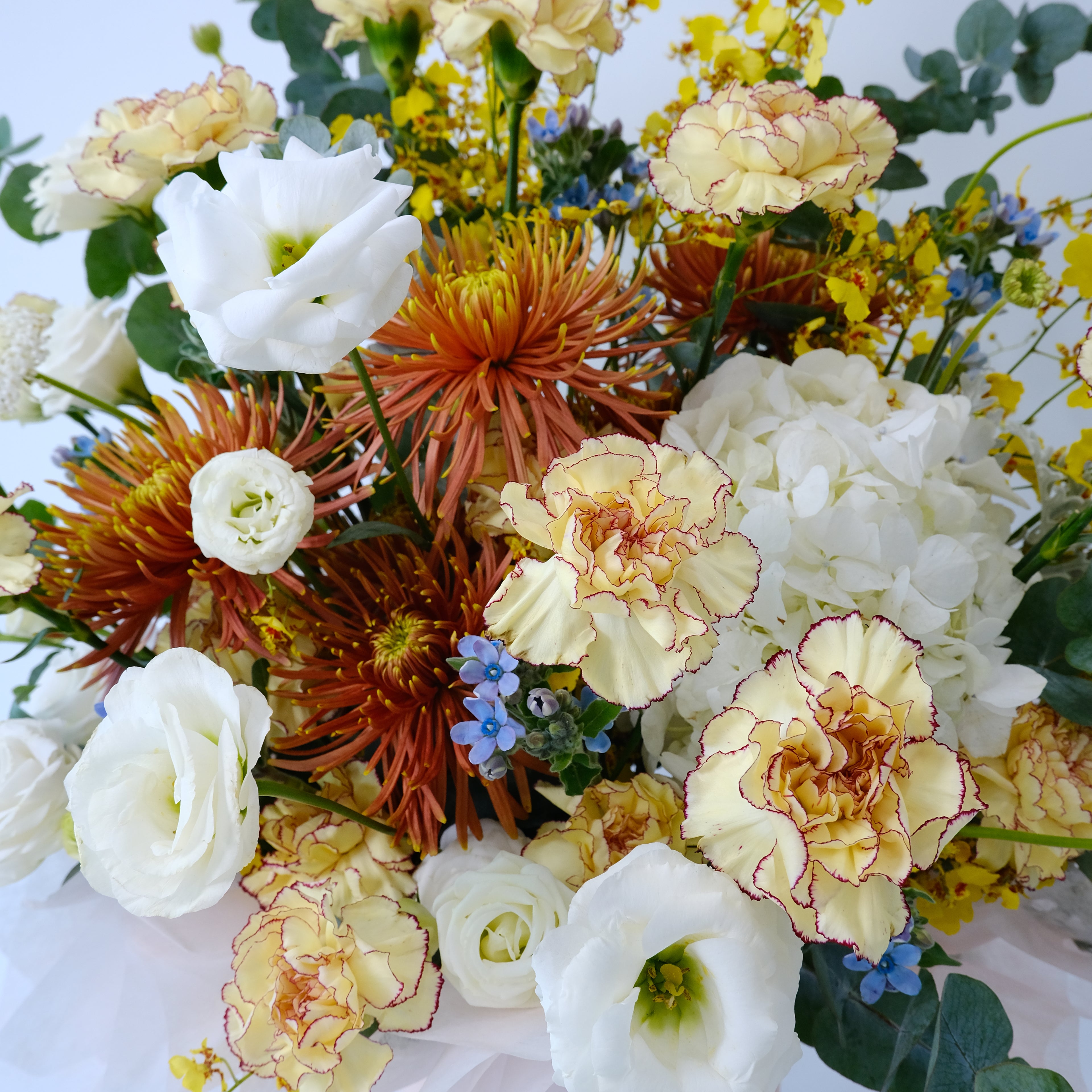Bouquet of colorful flowers including white, yellow, and orange with green leaves.