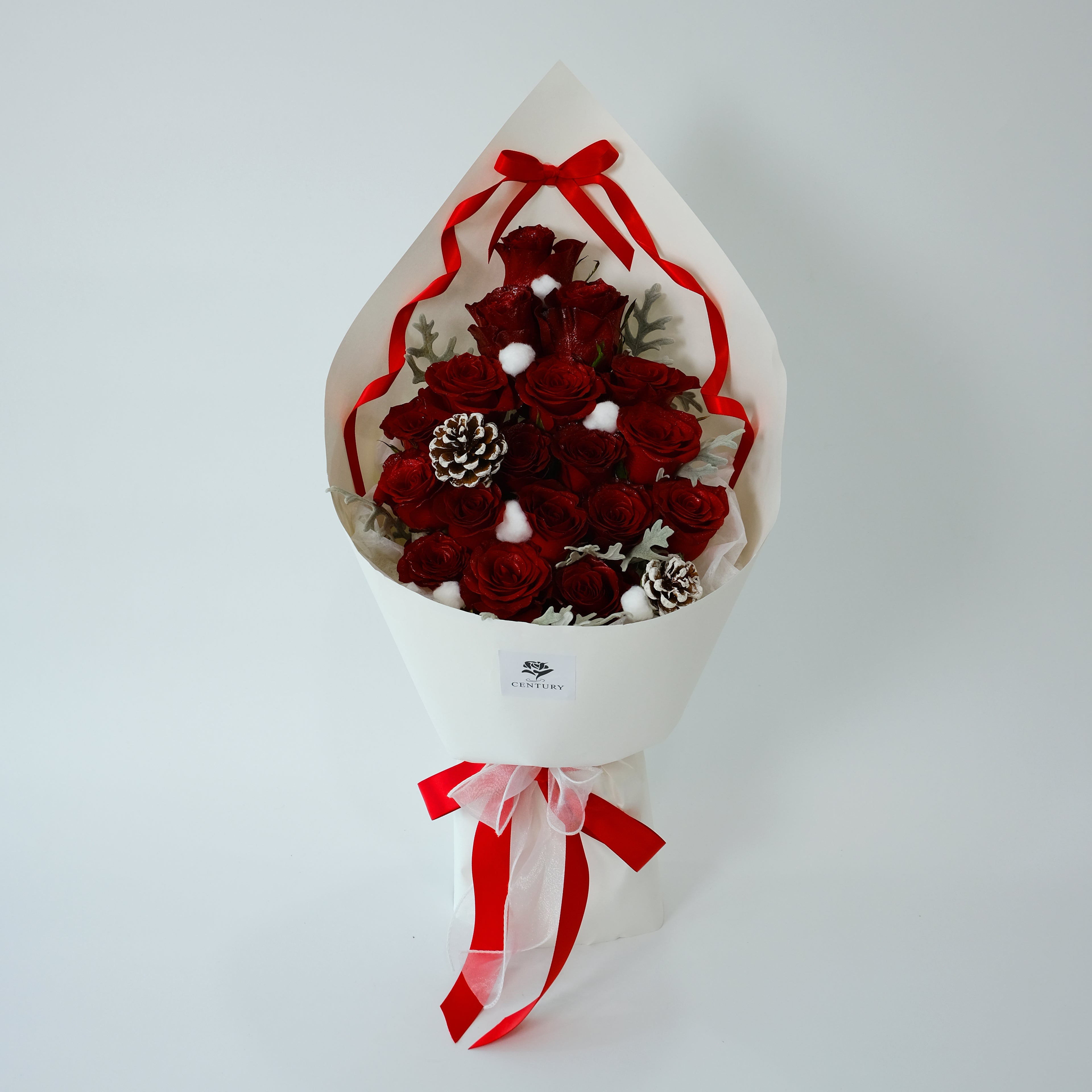 Bouquet of red flowers with pinecones and white berries in a white wrap with red ribbon on a light gray background