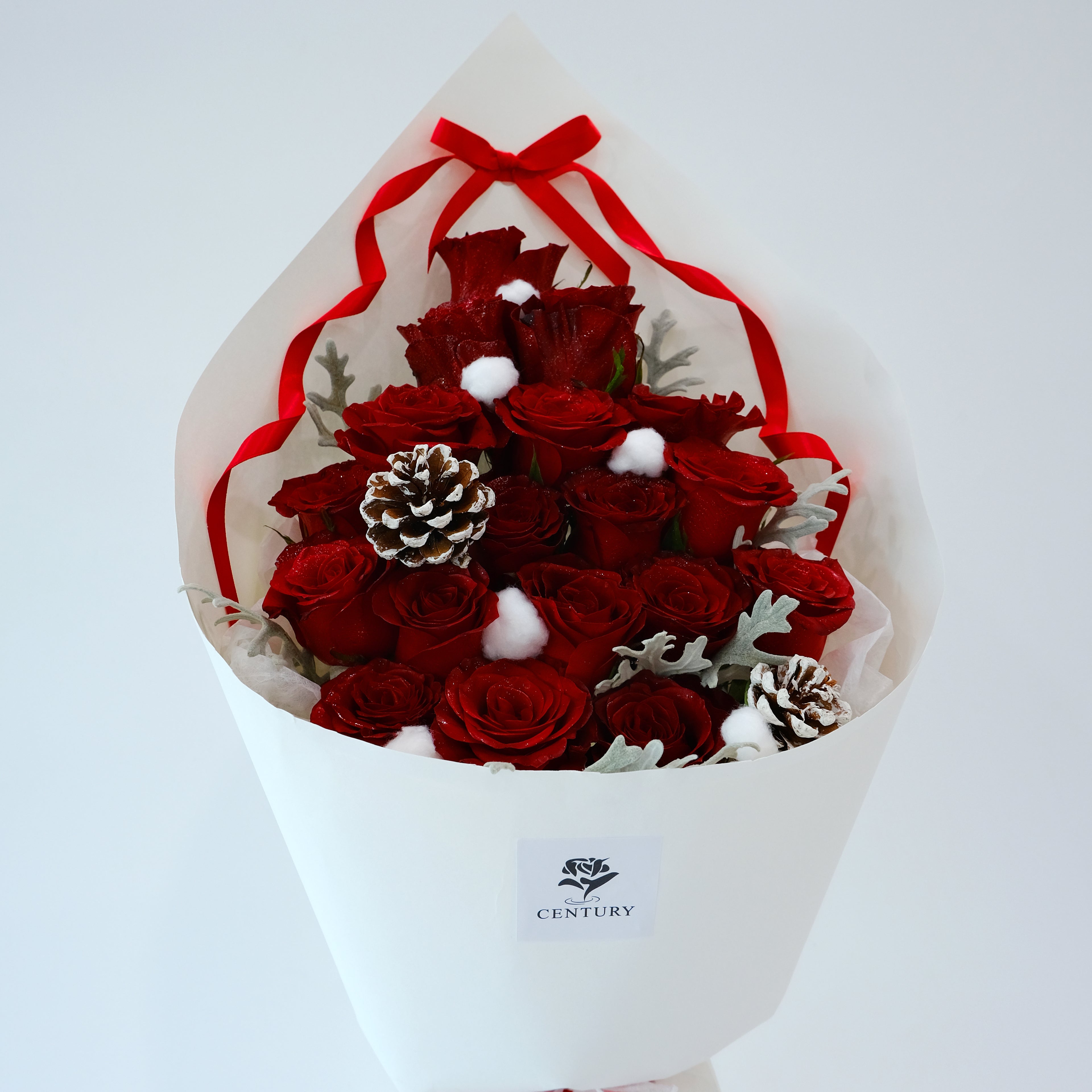 Bouquet of red roses with decorative elements in a white wrap, featuring the 'Century' brand.