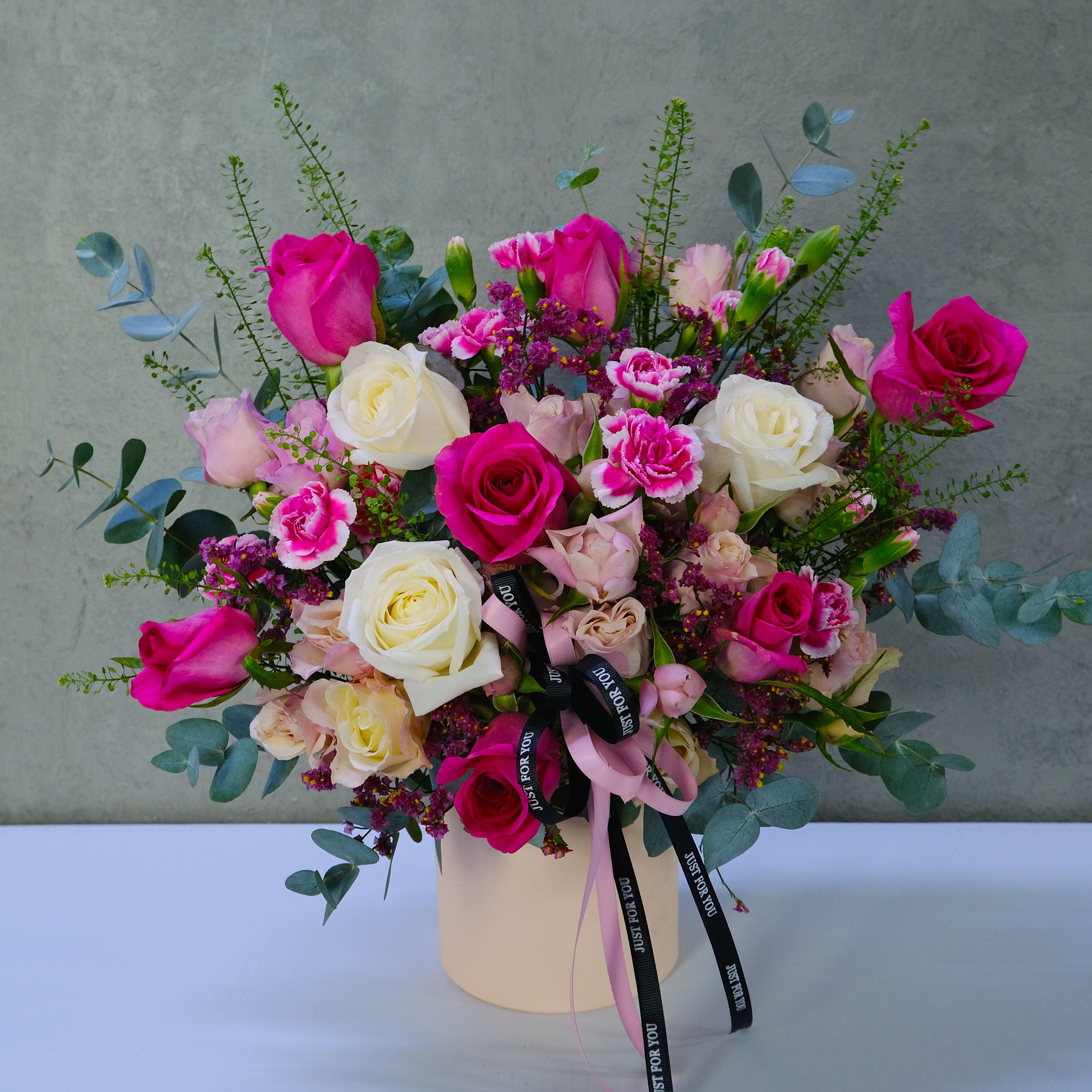 Bouquet of pink, white, and yellow roses in a box with a gray background