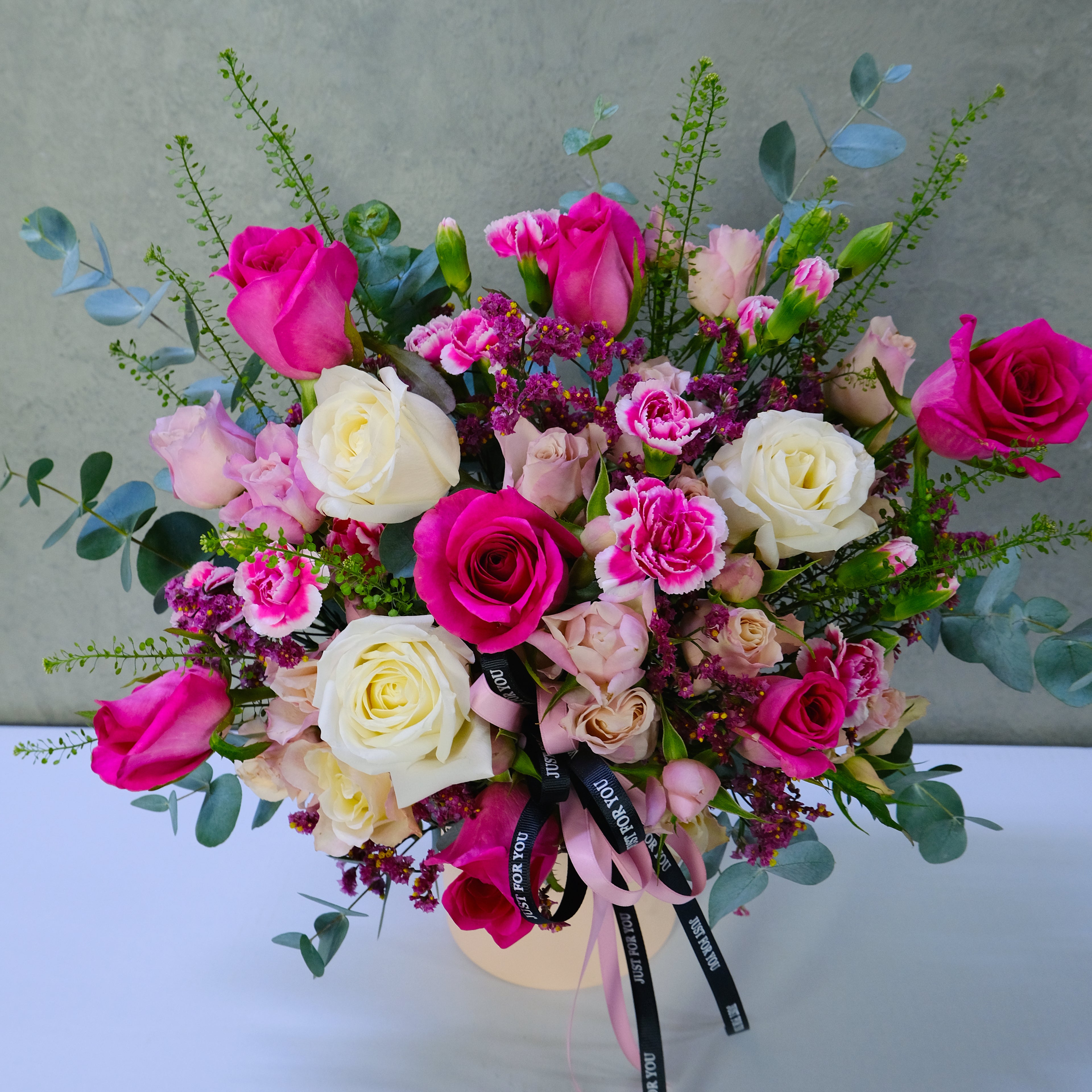 Bouquet of pink, white, and green flowers with a gray background
