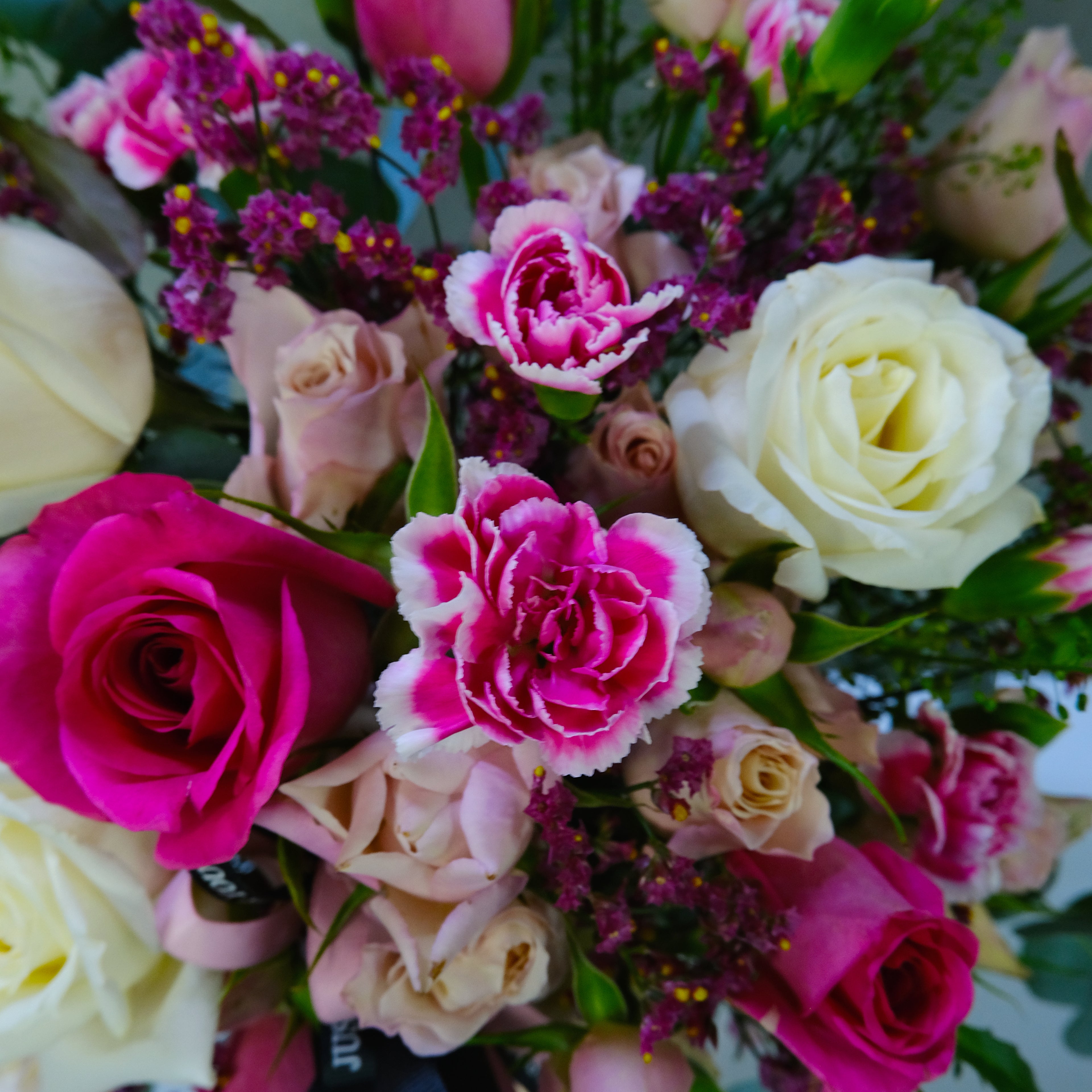Bouquet of colorful flowers including pink, white, and purple roses.