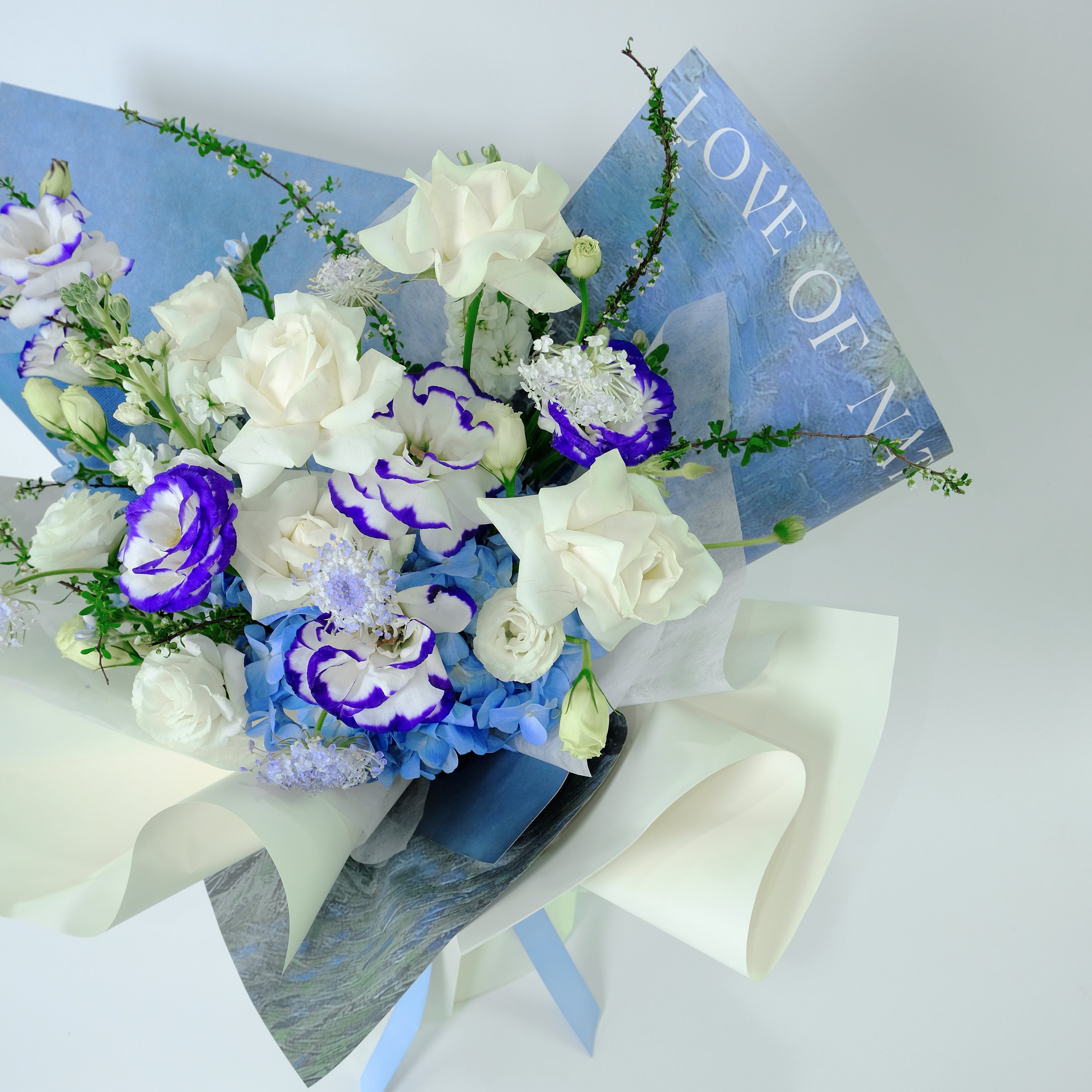 Premium Willow Bouquet featuring royal blue hydrangea, white roses, and blue-tipped lisianthus, wrapped in blue and cream paper for delivery in Kuala Lumpur.