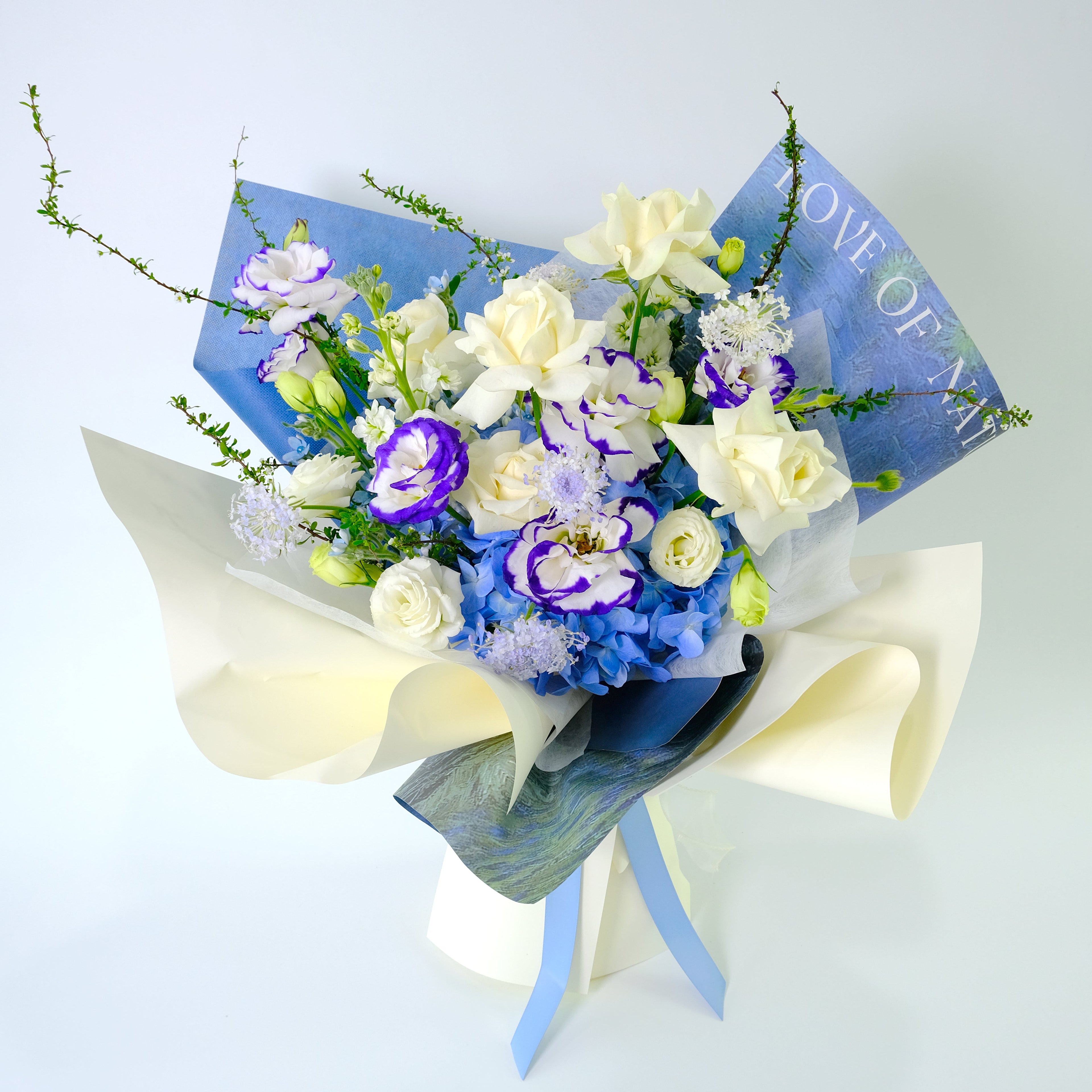 Premium Willow Bouquet featuring royal blue hydrangea, white roses, and blue-tipped lisianthus, wrapped in blue and cream paper for delivery in Kuala Lumpur.